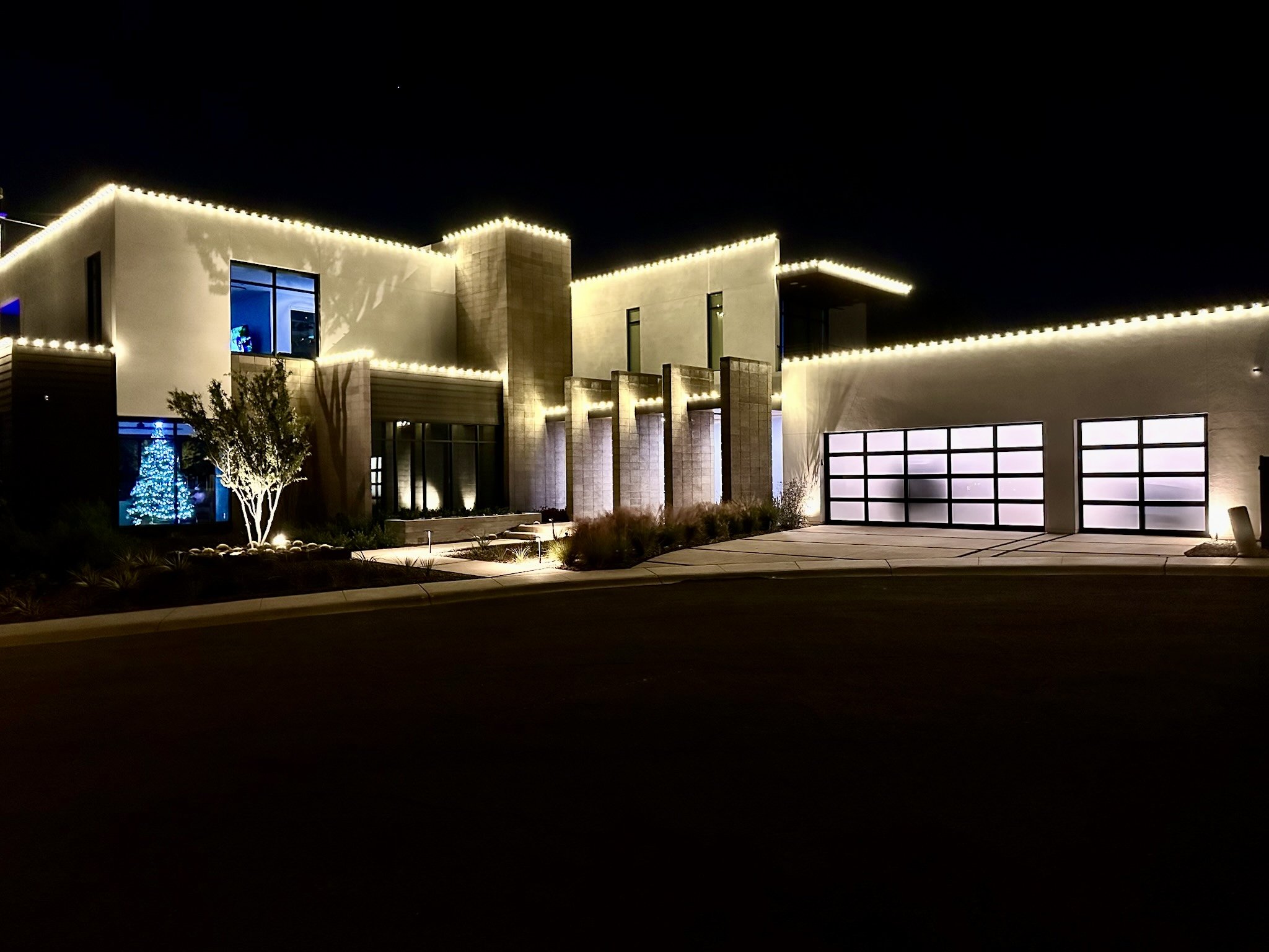 Warm white Christmas roofline lights on a modern Chandler AZ home at night