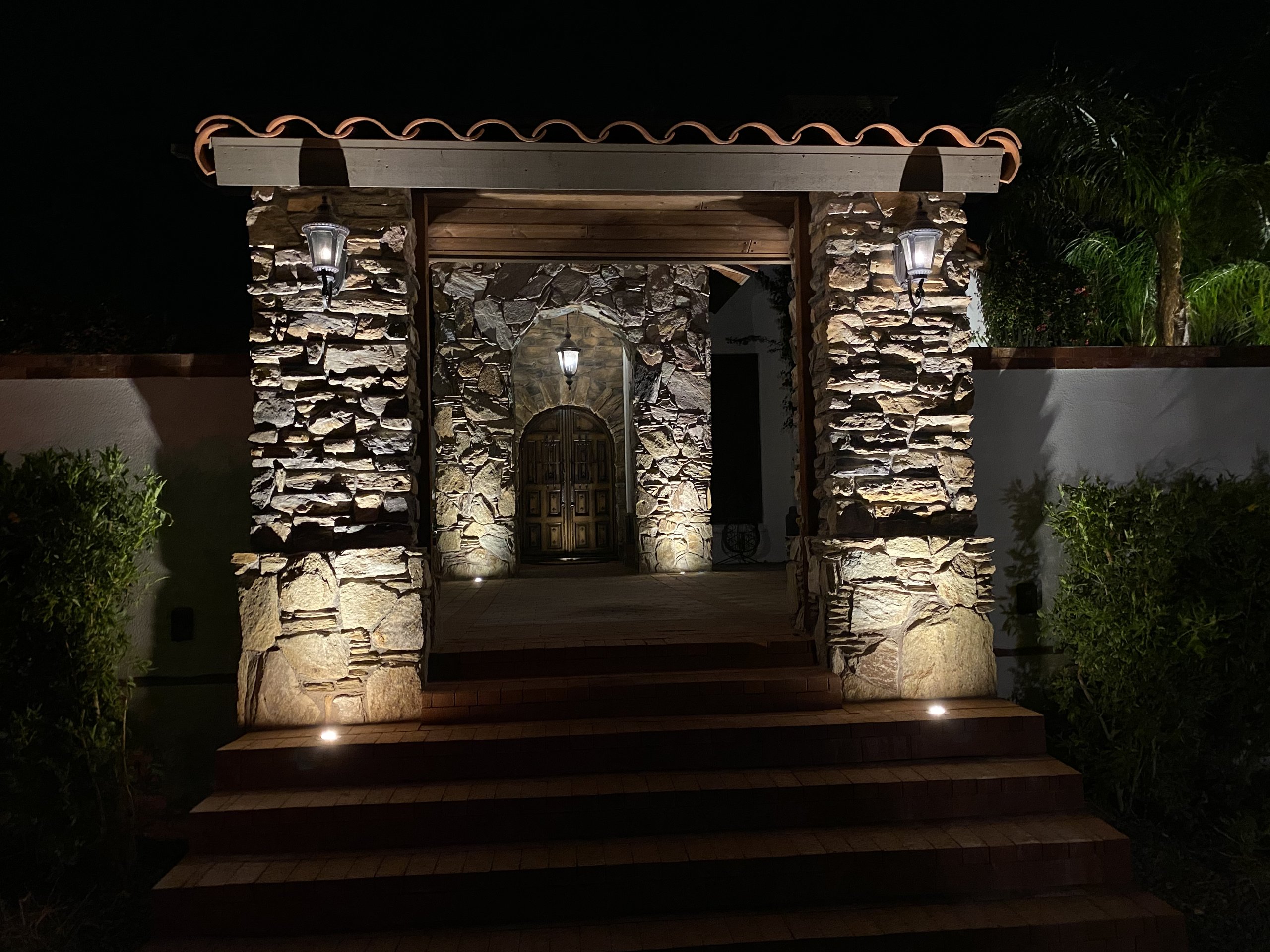 Landscape lighting on a stone entry gate with path and step lights at a Phoenix home at night