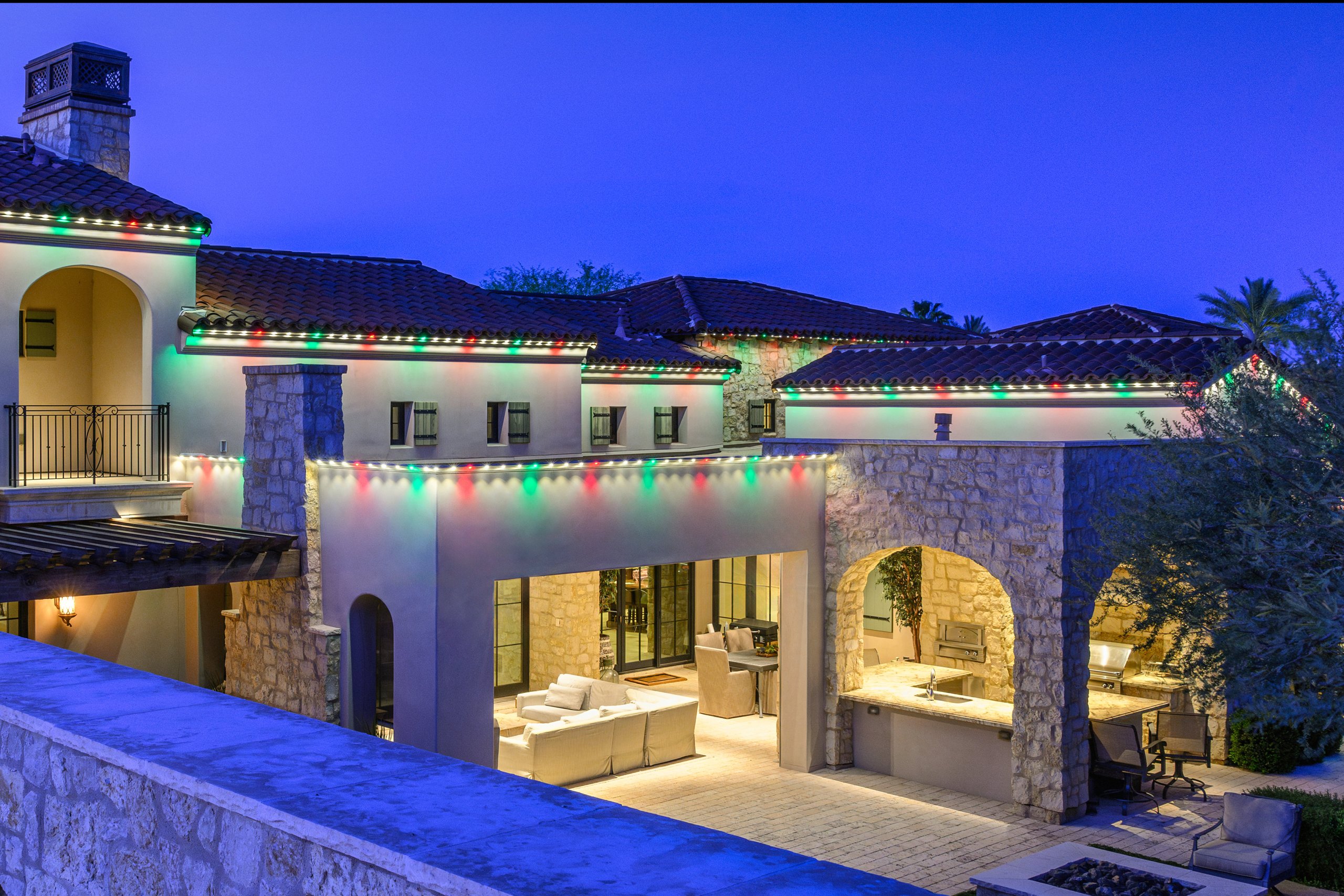 Red and green permanent trim lighting on a Mediterranean estate at dusk in Phoenix